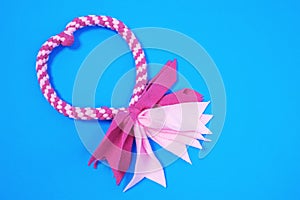 Cute pink fabric tug-of-war toy for dogs with rope handle for fun and games with beloved pet on blue background, top view, copy