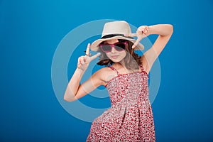 Cute playful little girl in hat showing victory sign