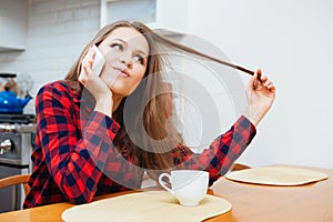 Cute playful woman talking on mobile phone and drinking coffee