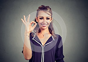 Cute playful young woman showing ok sign over gray background