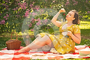 Cute plus size caucasian girl wearing a cute vintage yellow dress and enjoying a vacation in the summer Park on the green grass. c