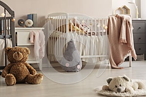 Cute plush toys and pink blankets in cozy bedroom interior for twin girls with two cribs and bedside cabinets. Real photo