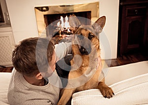 Cute portrait of young man and dog german shepherd hugging at cozy home in winter