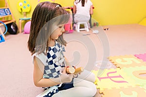Cute pre-school girl looking at a colorful puzzle play mat
