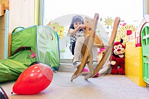 Cute pre-school girl swinging on a vintage wooden horse