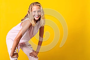 Cute pre-teen girl wearing fashion summer clothes posing on yellow background. 10 years old girl with beauty eyes, blonde hairl