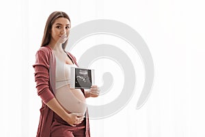 Cute Pregnant Lady Posing With Baby Sonography Photo Near Window At Home