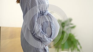 Cute pregnant woman holds her hand on her belly. Concept of a happy pregnancy. 9 months of waiting