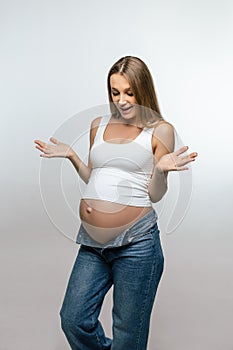 Cute pregnant woman in jeans looking happy and excited