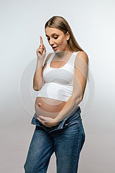 Cute pregnant woman in jeans looking happy and excited
