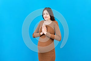 cute pregnant woman praying on colored background 