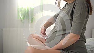 A cute pregnant woman sits in bed. The concept of a happy pregnancy. 9 months of waiting for a baby.