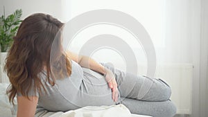 A cute pregnant woman sits in bed. The concept of a happy pregnancy. 9 months of waiting for a baby.