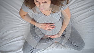 A cute pregnant woman sits in bed. The concept of a happy pregnancy. 9 months of waiting for a baby.