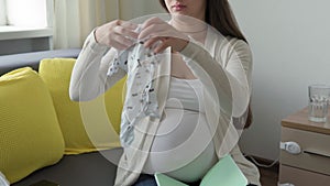 Cute pregnant woman writing packing list for maternity hospital notebook prepares bag. Young lady in pregnancy have fun