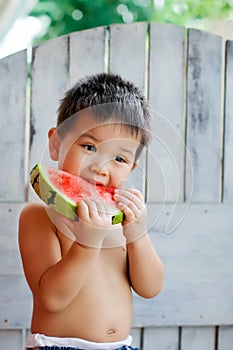 Cute preschool-aged boy enjoying a slice of watermelon on a hot day