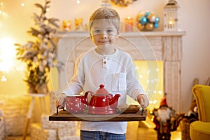 Cute preschool child, blond boy with pet dog, playing in decorated Christmas room