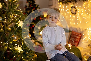 Cute preschool child, blond boy with pet dog, playing in decorated Christmas room