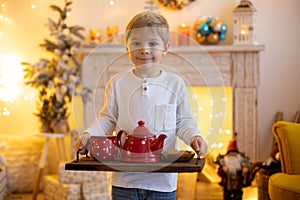 Cute preschool child, blond boy with pet dog, playing in decorated Christmas room