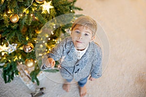 Cute preschool child, blond boy with pet dog, playing in decorated Christmas room