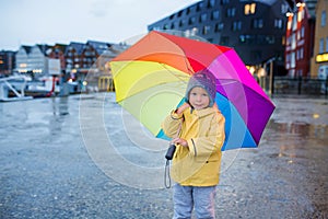 Cute preschool child, boy, holding rainbow umbrella in Tromso on a rainy day