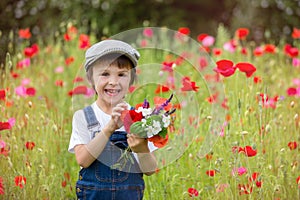 Cute preschool child in poppy field, holding a bouquet of wild f