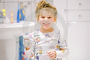 Cute preschool girl in pajamas after taking bath. Happy smiling child with wet long hair playing with toy socks, having