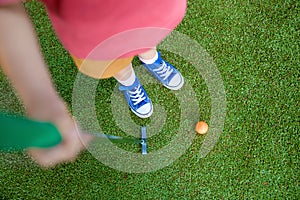 Cute preschool girl playing mini golf with family. Happy toddler child having fun with outdoor activity. Summer sport