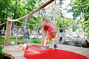 Cute preschool girl playing mini golf with family. Happy toddler child having fun with outdoor activity. Summer sport