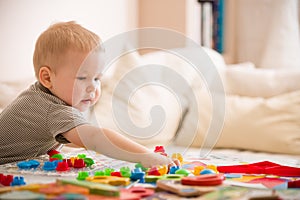 Cute preschooler child boy plays with mosaic at home. A blond little toddler playing in kid`s room. Leisure activities. indoors.