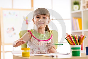 Cute preschooler child girl drawing with pencils in nursery