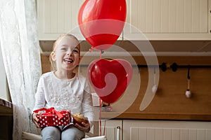 Cute preschooler girl celebrating 6th birthday. Girl holding her birthday cupcake and beautifully wrapped present.