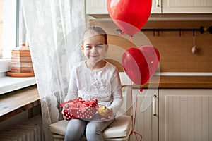 Cute preschooler girl celebrating 6th birthday. Girl holding her birthday cupcake and beautifully wrapped present.