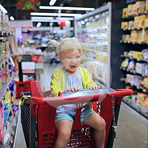 Cute preschooler girl in shopping cart