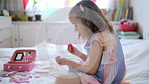 Cute preschooler girl with unicorn hair decoration playing with children cosmetic and applying makeup.