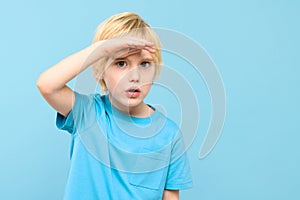 Cute preschooler looking curiously into distance with hand on the forehead. Kid looking into future.