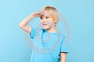 Cute preschooler looking to distance with hand on the forehead, smiling. Kid looking into future.