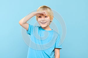 Cute preschooler looking to distance with hand on the forehead, smiling. Kid looking into future.