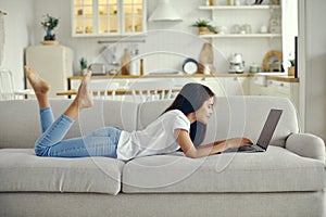 Cute preteen 12s girl use laptop lying on couch