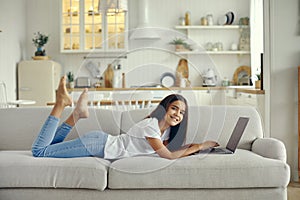 Cute preteen 12s girl use laptop lying on couch