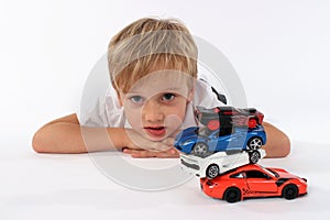 Cute preteen boy lying with a pile of car toys and making a confused look in his face