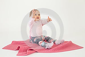 Cute pretty baby girl sitting on floor with plaid