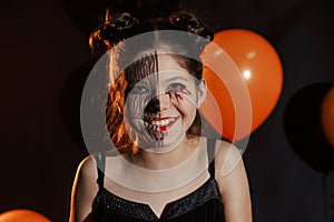 Cute and pretty girl with long curls posing for halloween wearing a huge black and orange hat