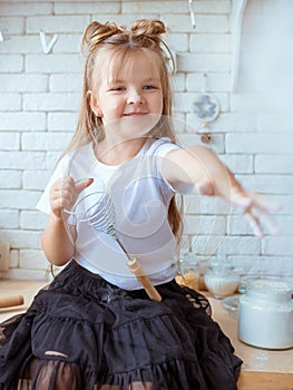 Cute pretty little caucasian girl with long hair in white t-shirt and black skirt cooking in the kitchen