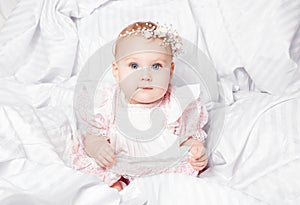 Cute and pretty young baby girl in nice dress over white blanket