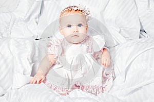 Cute and pretty young baby girl in nice dress over white blanket