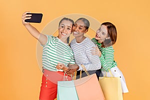 Cute pretty young multiracial ladies taking selfie while shopping