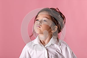 Cute proud little girl in white shirt on pink background. Human emotions and facial expression