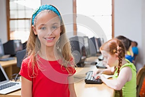 Cute pupil in computer class smiling at camera