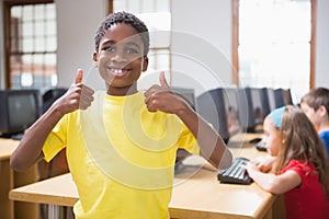 Cute pupil in computer class smiling at camera